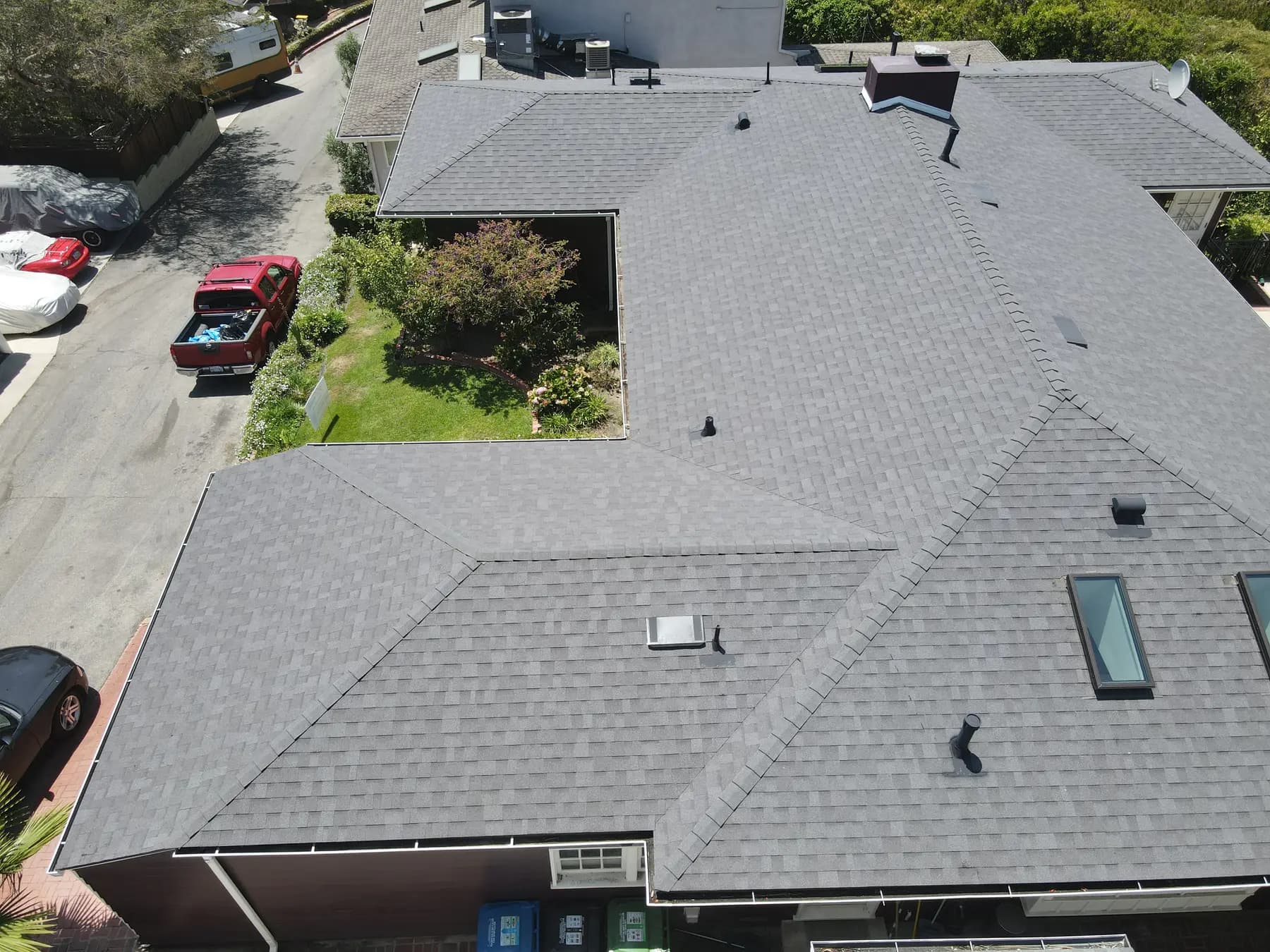 The front of the home from above, with the new gray shingles, the chimney, skylights and pipe vents