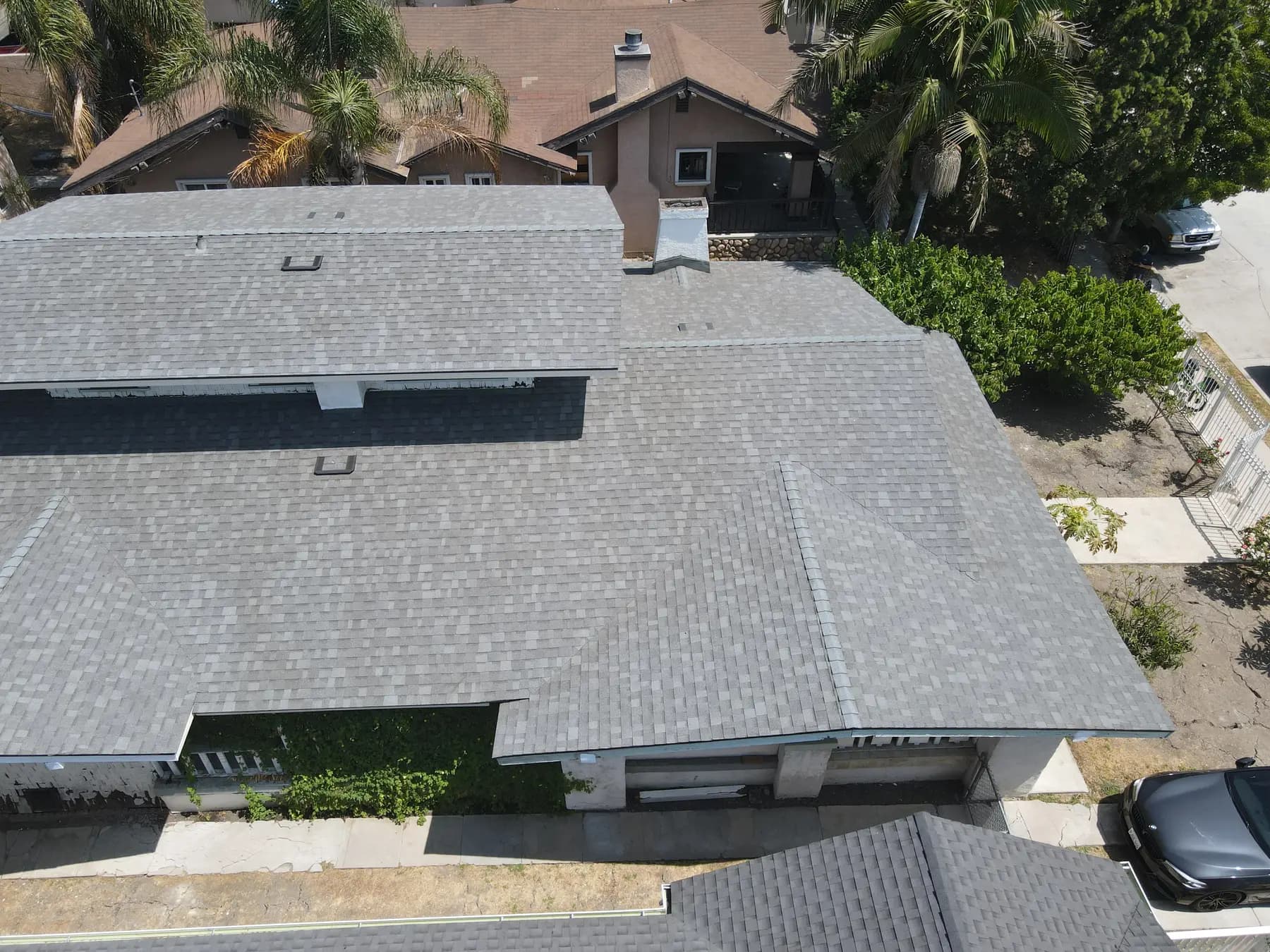 The side of the roof, with two gables, a chimney and box vents set into the new gray shingles