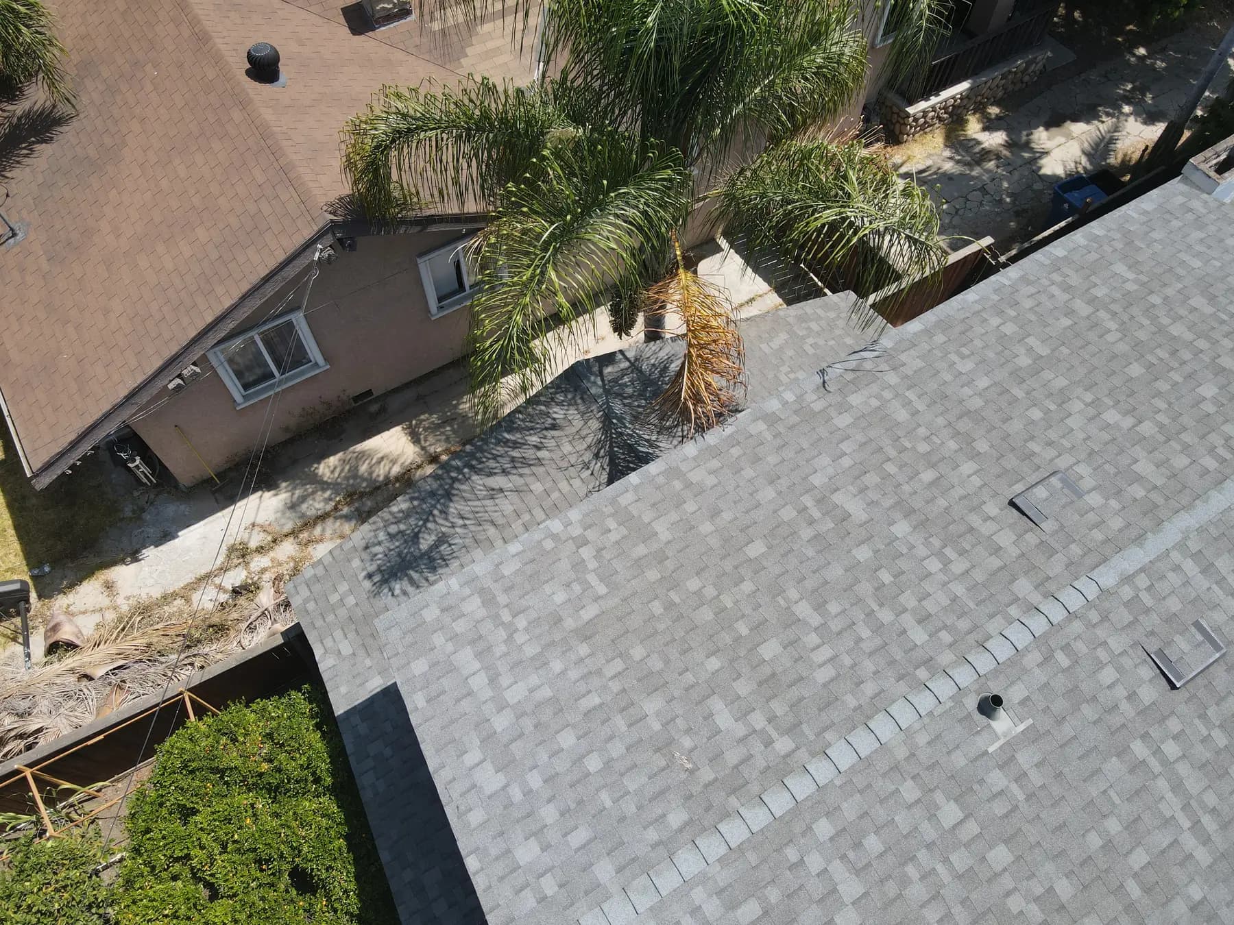 Close view along a hip, with the ridge cap, a box vent and a pipe vent in the new shingles