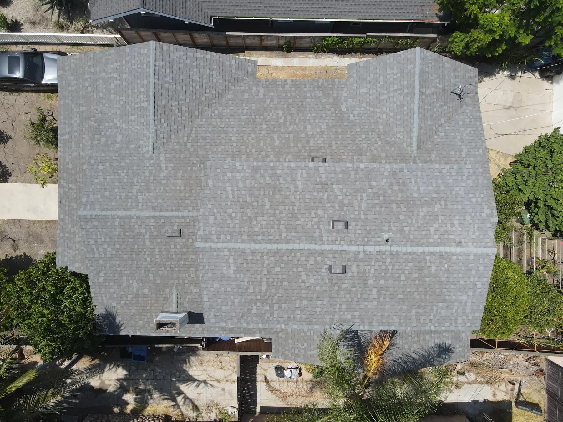 Another top-down view of the roof, with its even gray shingles and the vents set across it