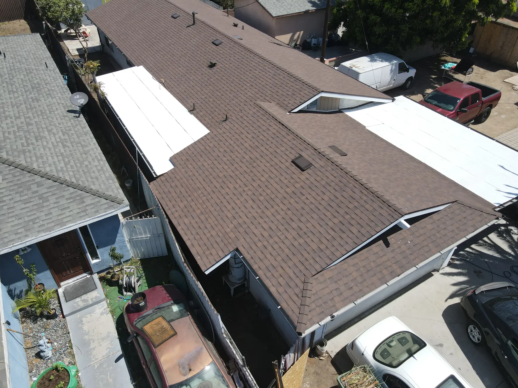 Overhead view along the long shingle roof, with its two gabled vent openings and the white flat sections on each side