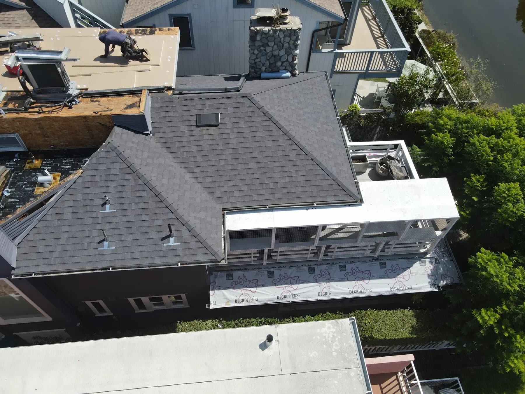 The finished charcoal shingle roof beside the stone chimney on a canal-side home in Venice