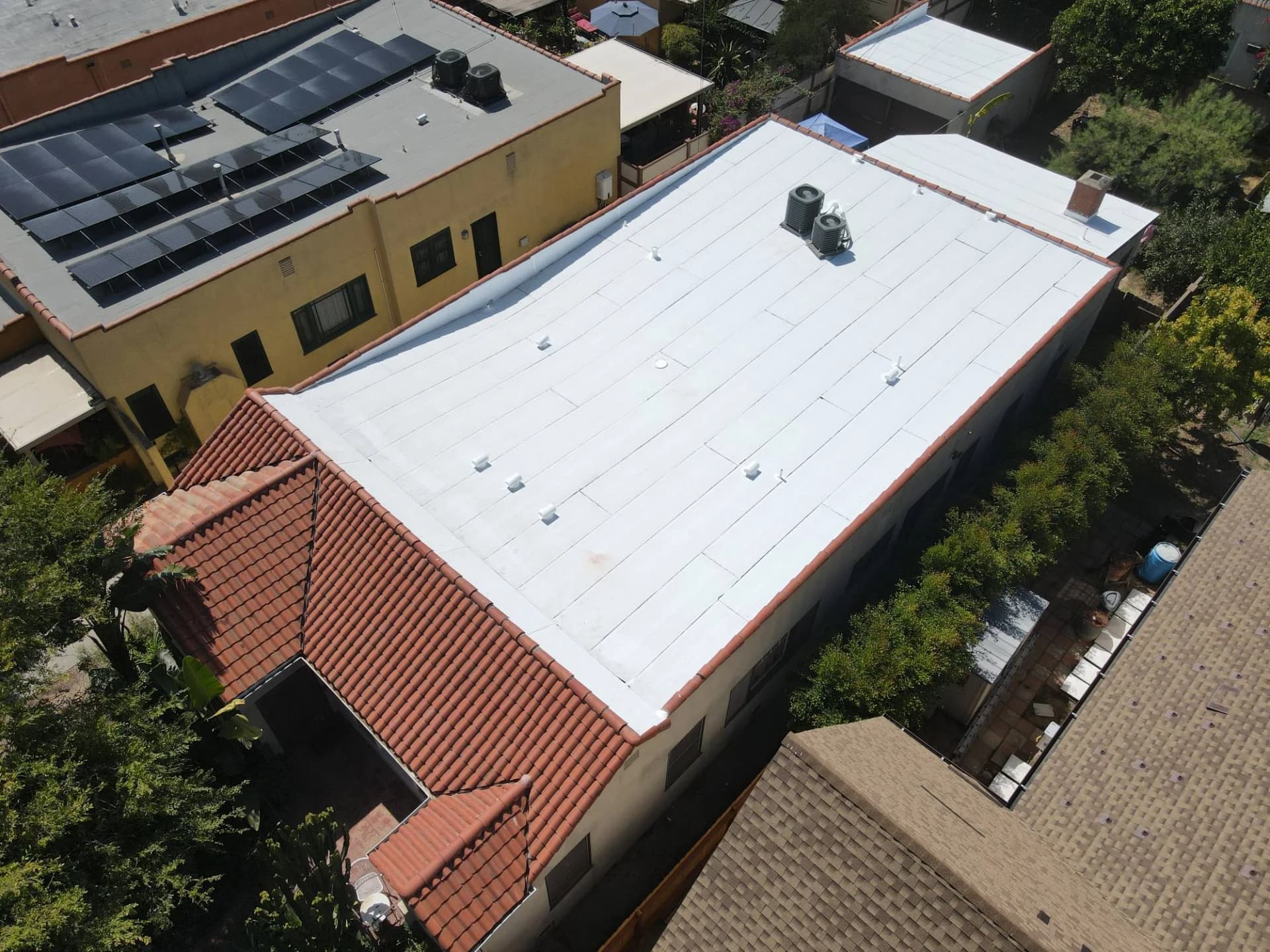 Aerial view of a white flat roof with a clay tile edge and rooftop equipment