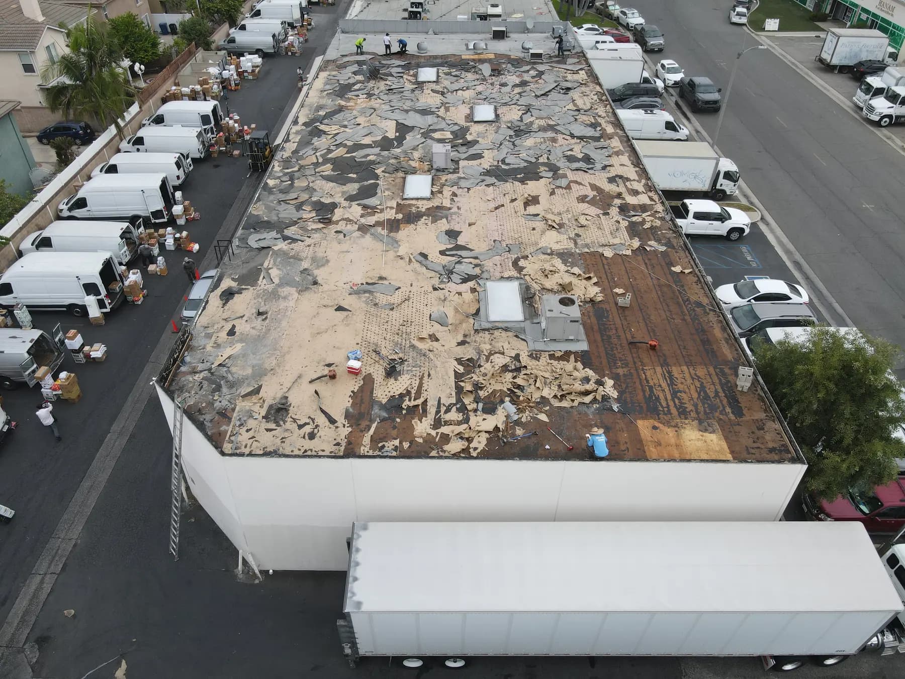 Tear-off day: the old roof stripped across most of the building, with torn base sheet over the wood deck and the skylights and AC units still in place