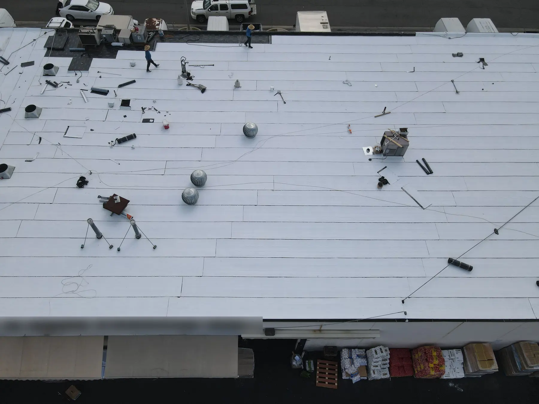 Straight-down view of the new white cap sheet in long rows, around the turbine vents, vent pipes and rooftop units