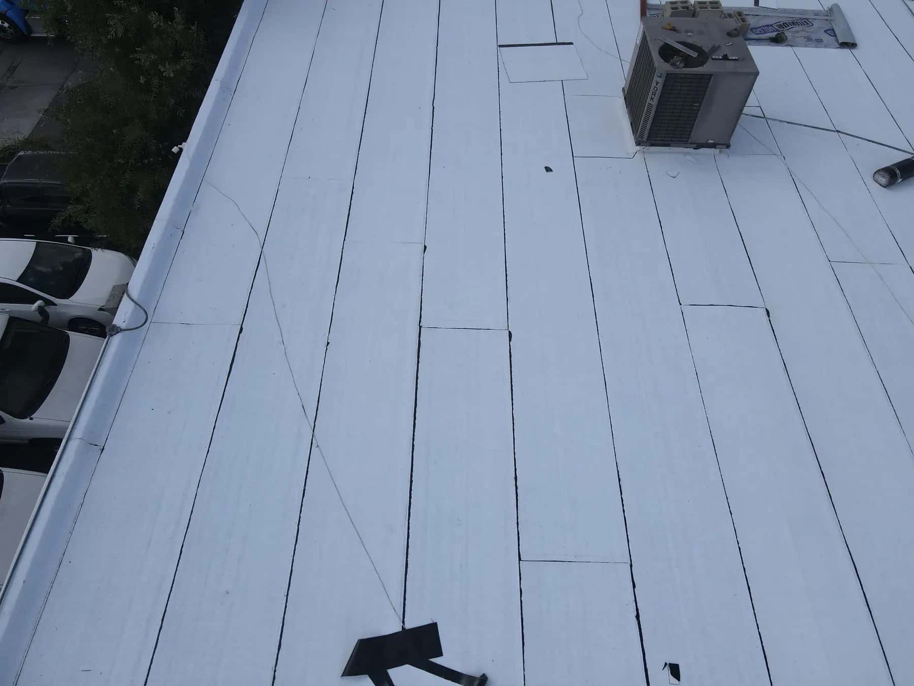 Rows of new white cap sheet with sealed laps along the parapet edge of a commercial flat roof in Westminster