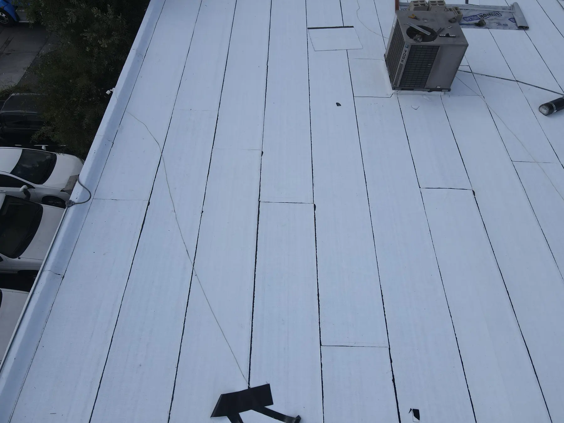 Rows of new white cap sheet with sealed laps along the parapet edge of a commercial flat roof in Westminster