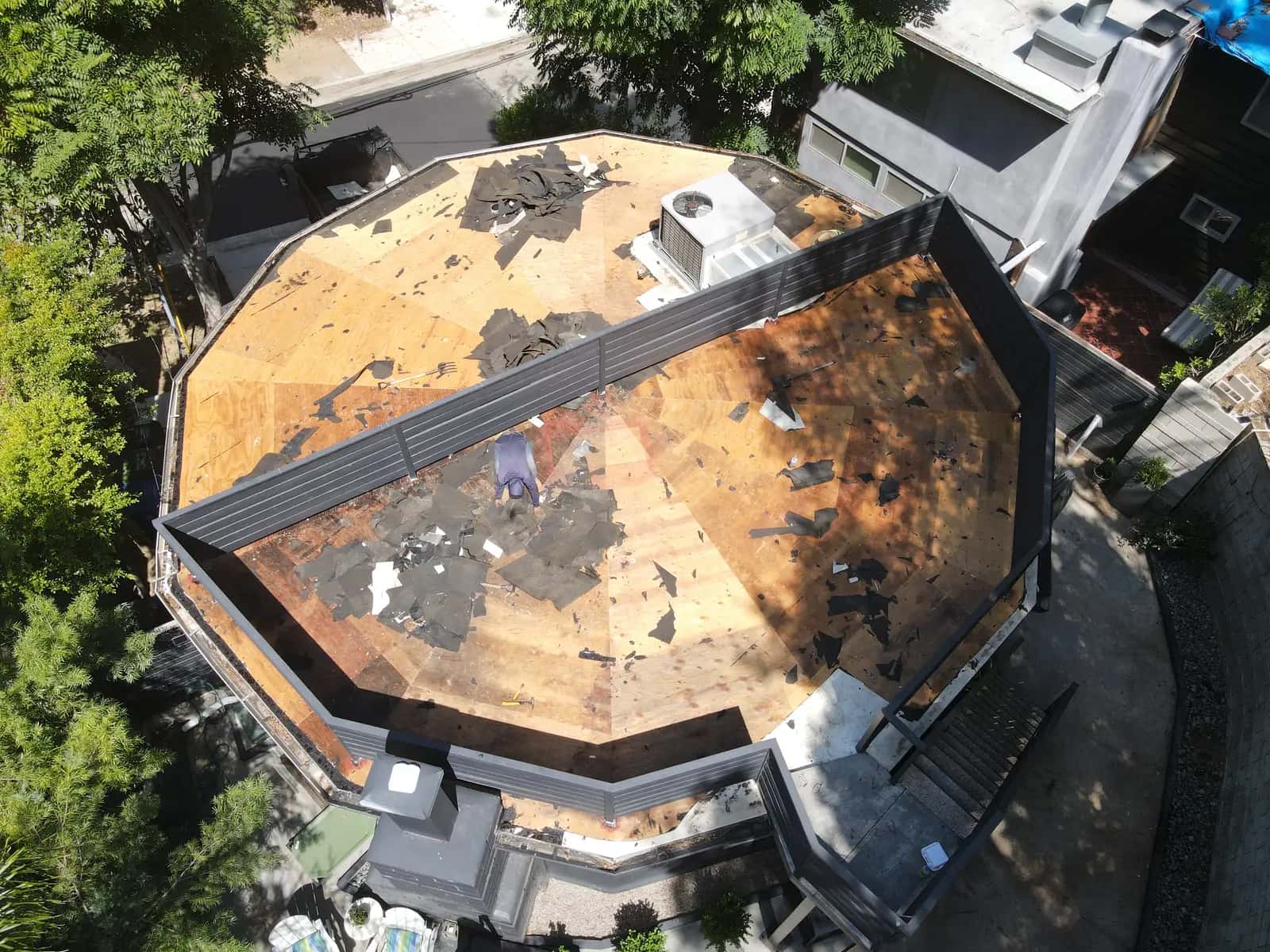 Round, 12-sided roof stripped to the plywood deck during the tear-off, with the rooftop deck railing across the middle
