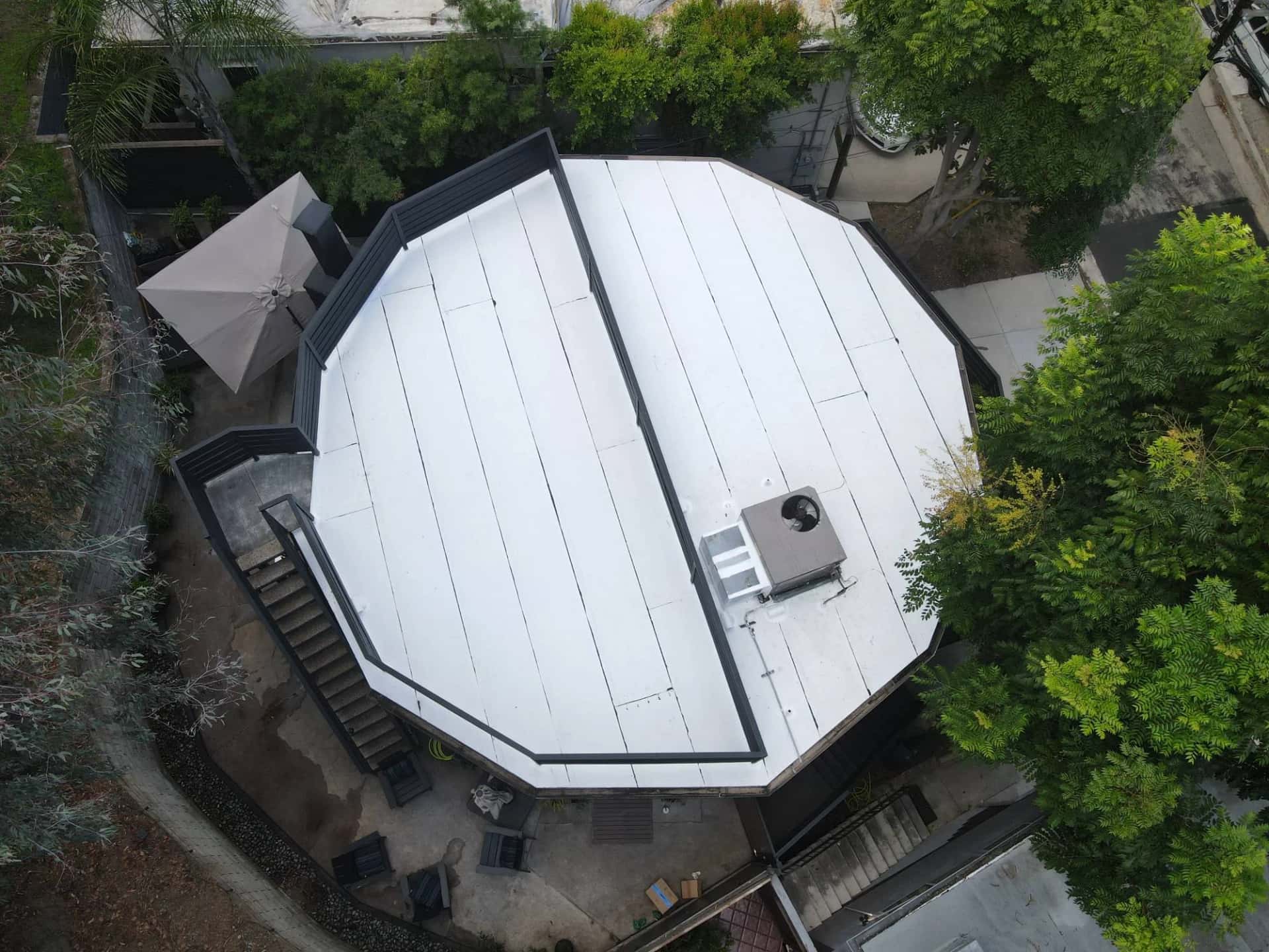 Finished white reflective flat roof on a round, 12-sided home in the Hollywood Hills, with the rooftop deck railing and HVAC unit