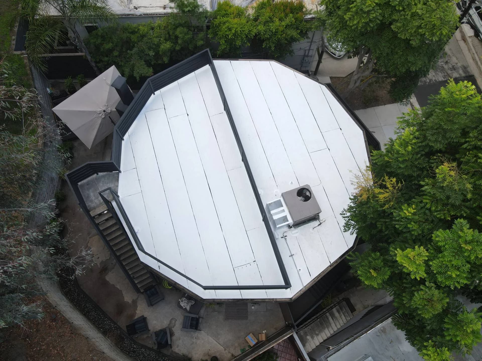 Finished white reflective flat roof on a round, 12-sided home in the Hollywood Hills, with the rooftop deck railing and HVAC unit