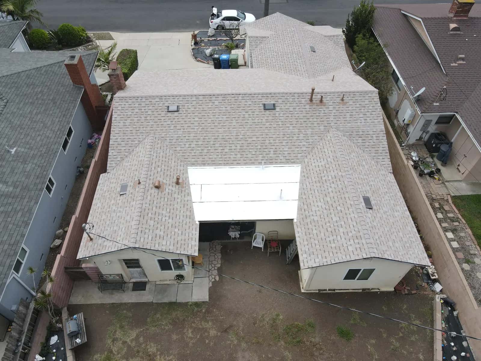Aerial view of the new tan shingle roof and the white reflective flat roof over the back patio of the single-story home