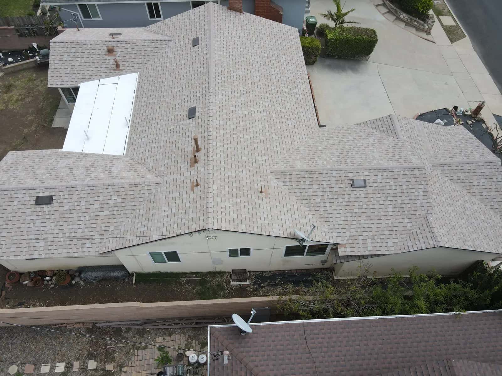 Rear view of the new tan shingle roof and the white reflective flat roof over the patio