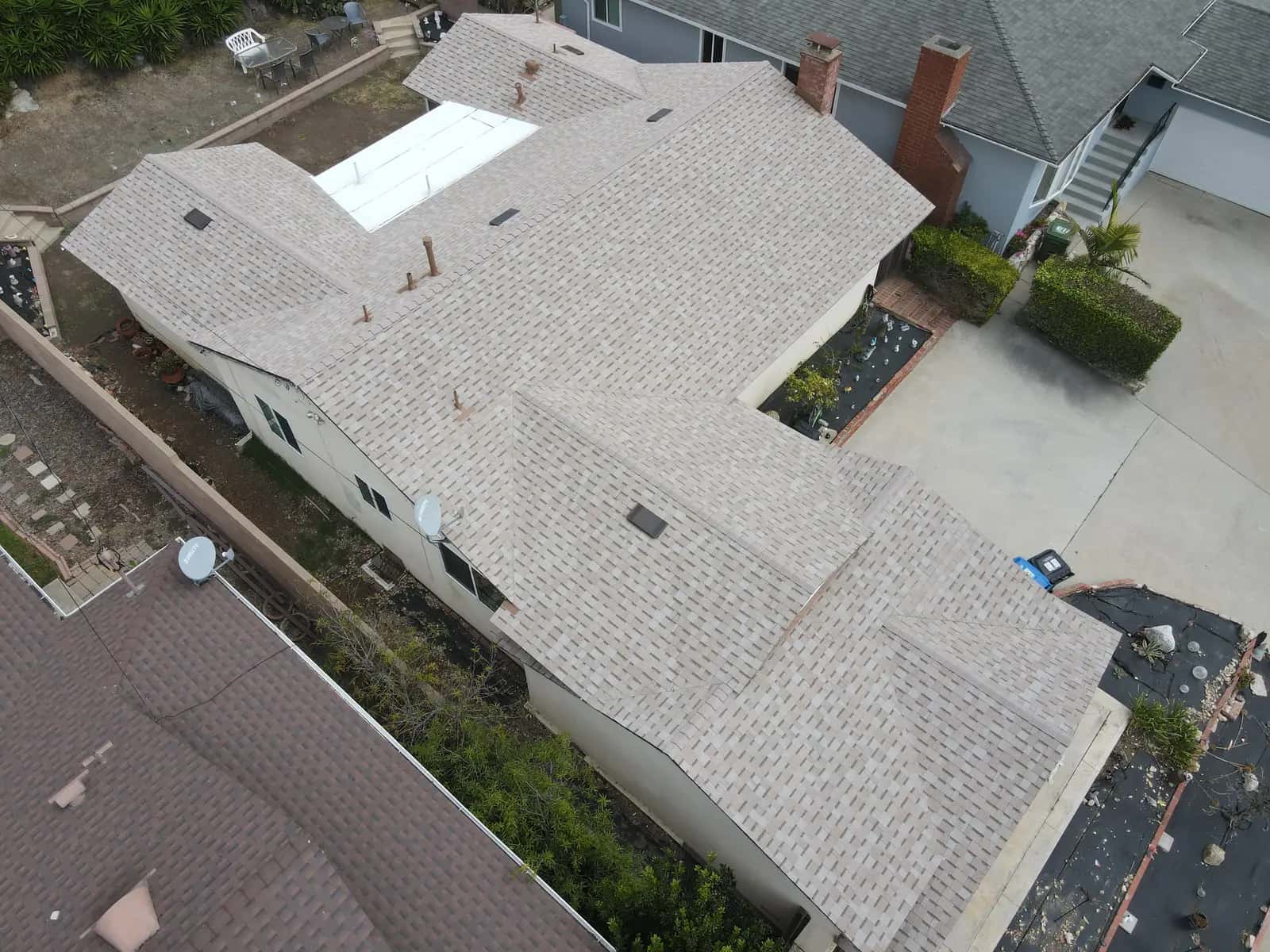 Aerial view along the side of the home, with the new shingle roof, white patio cover and brick chimney