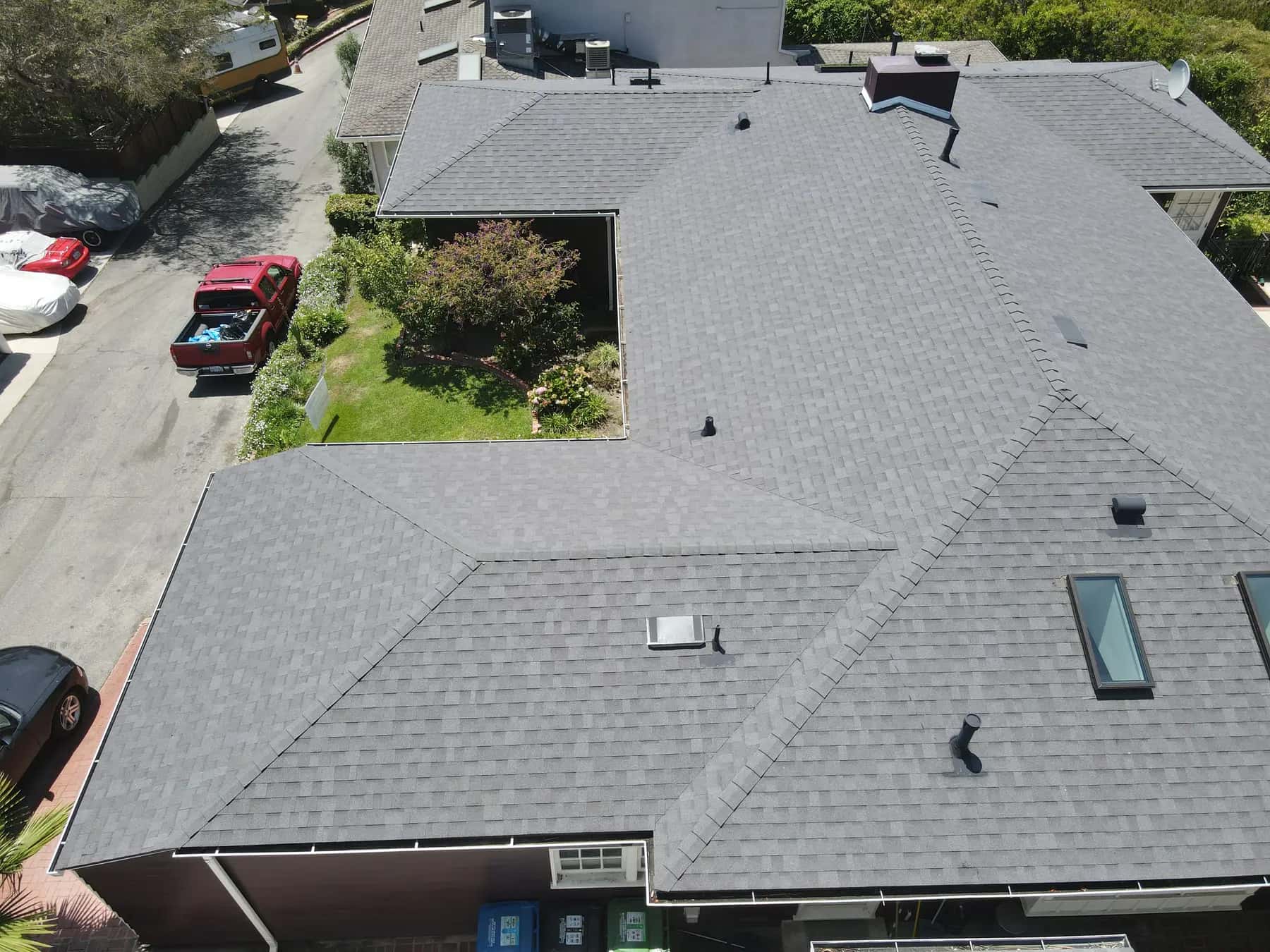 The front of the home from above, with the new gray shingles, the chimney, skylights and pipe vents