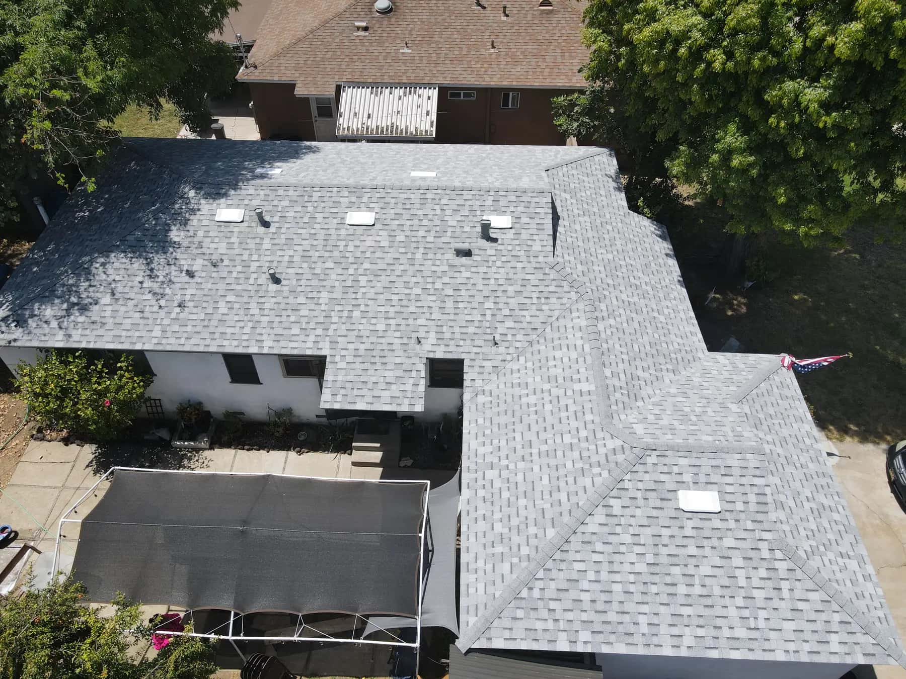 Another overhead view of the roof, showing the hips, valleys and vents against the yard and patio