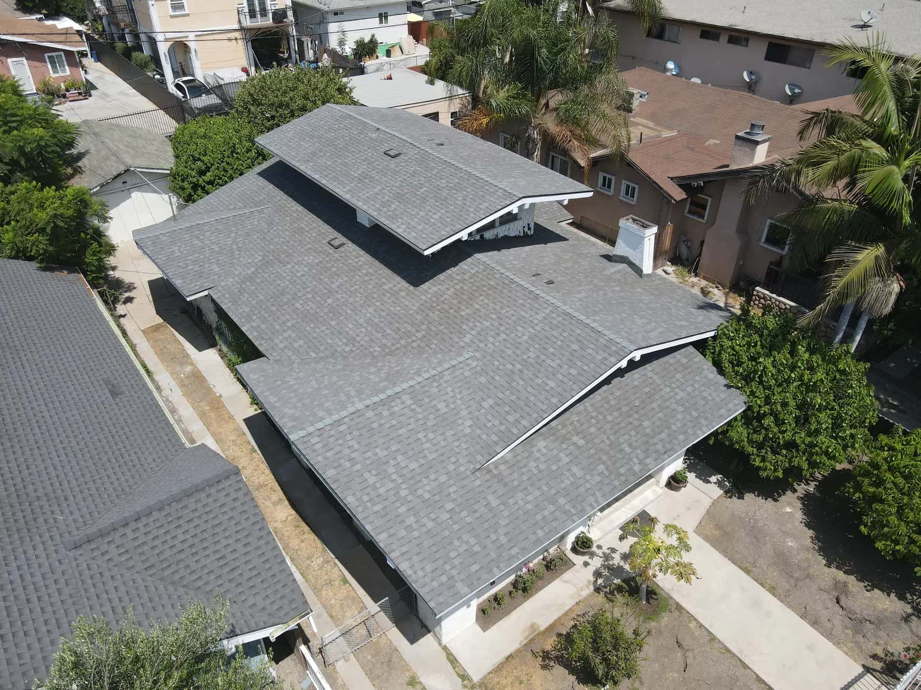 Angled aerial view of the multi-gable roof, with its new shingles, ridges and valleys running clean