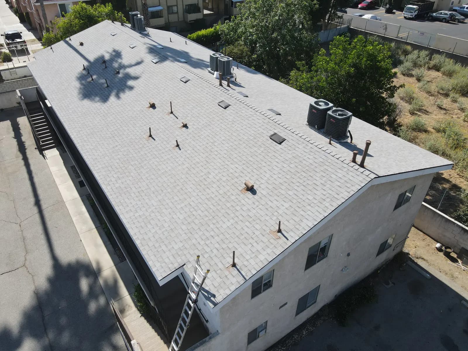Aerial view of the new light gray shingle roof on a two-story apartment building in Panorama City