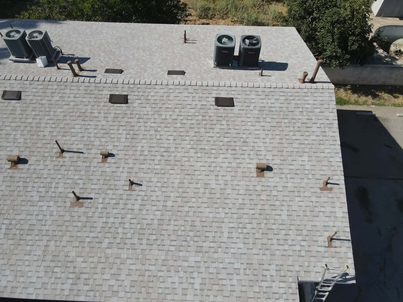 AC condensers and flashed pipe jacks on the light gray shingle roof