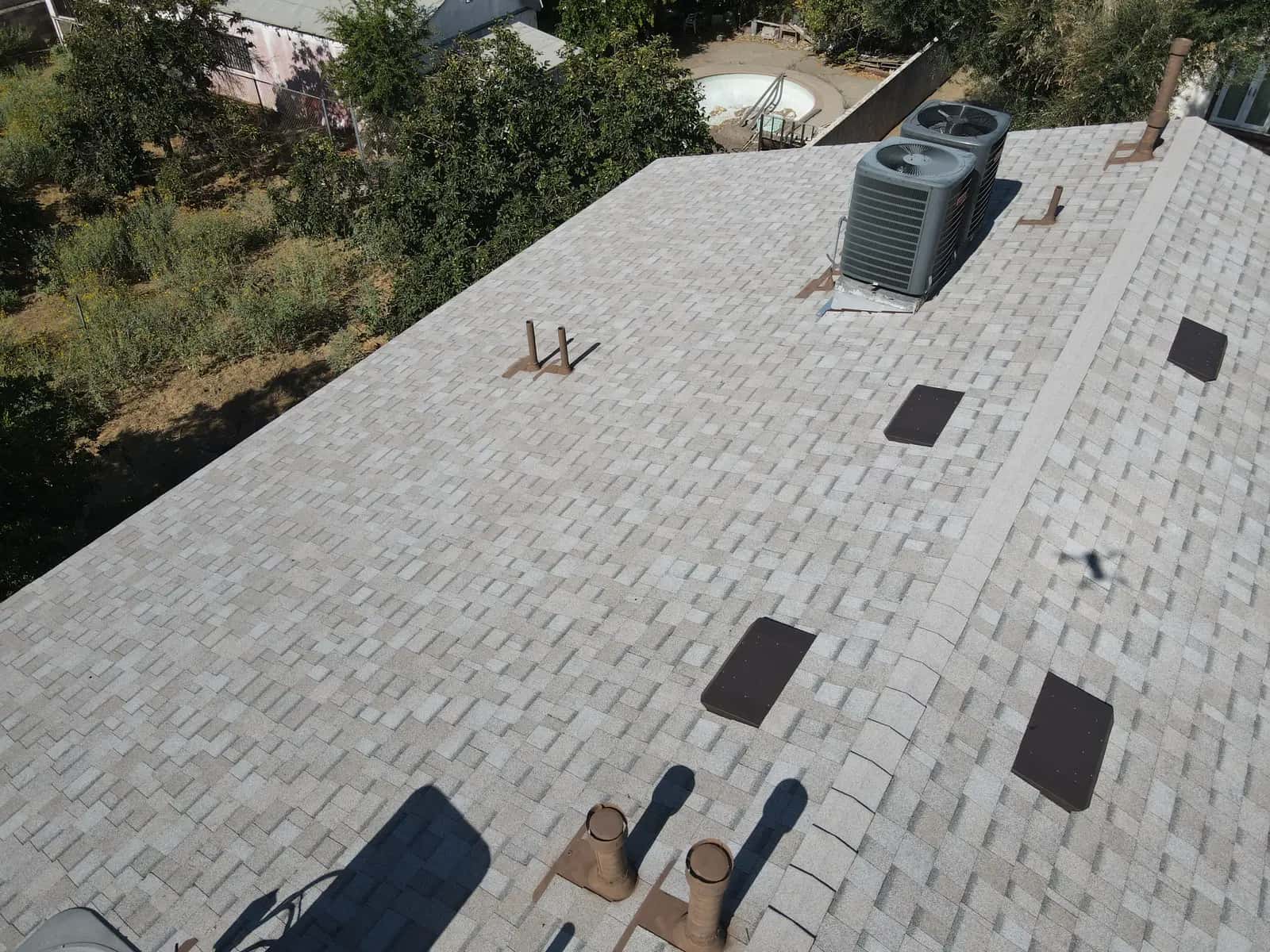 An AC condenser on its flashed platform near the roof ridge