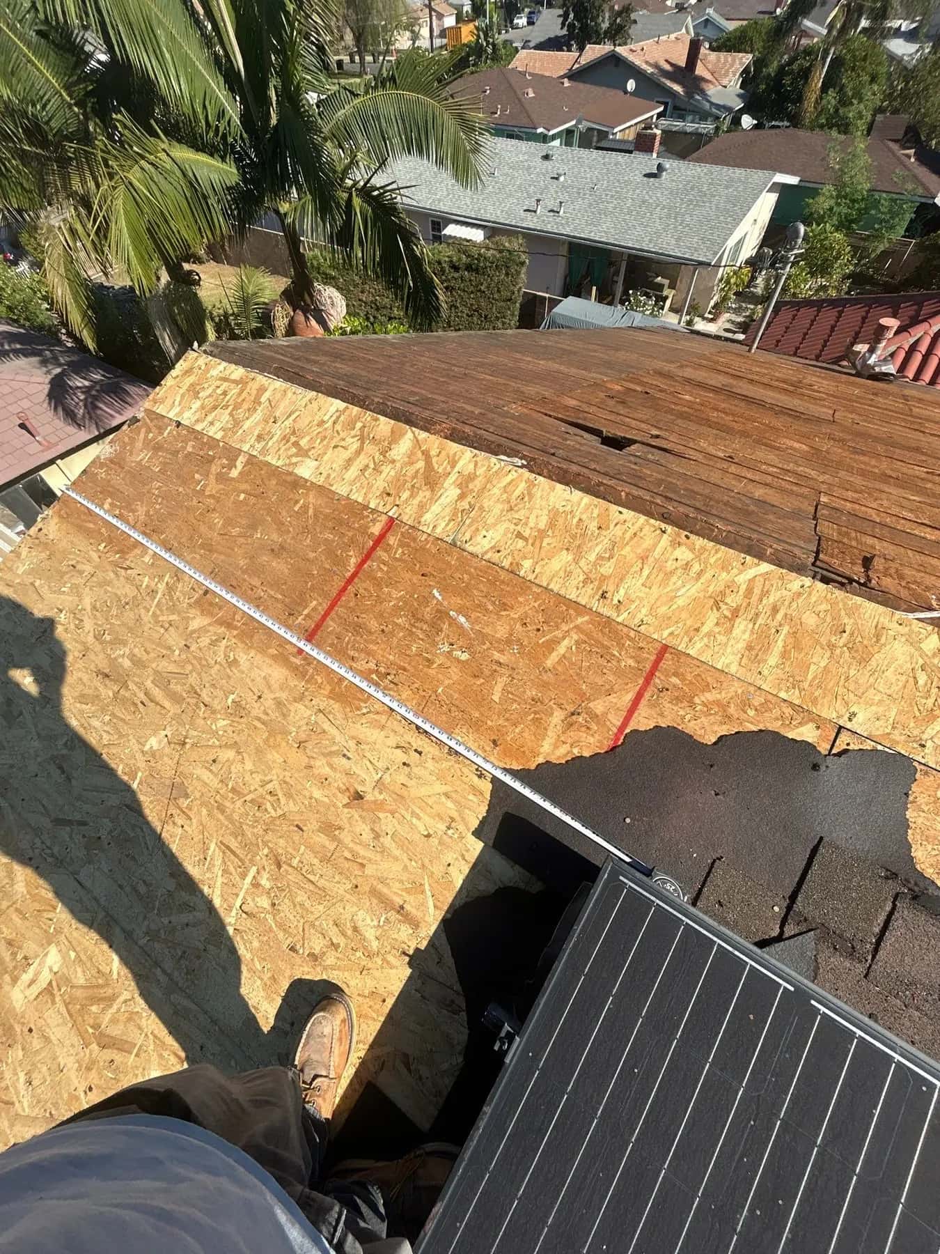 Chalk lines and a tape measure on the new sheathing, marking the array’s position on the roof
