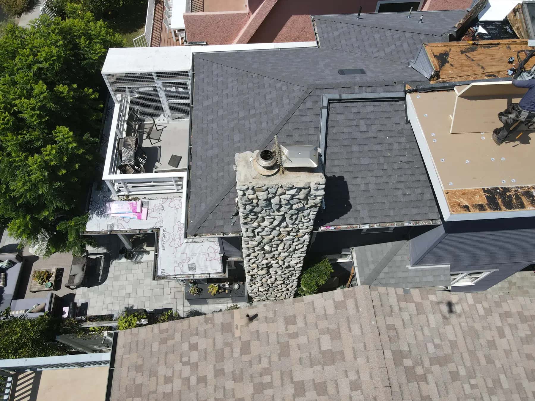 River-stone chimney and the new shingle roof, with new boards across the upper flat section