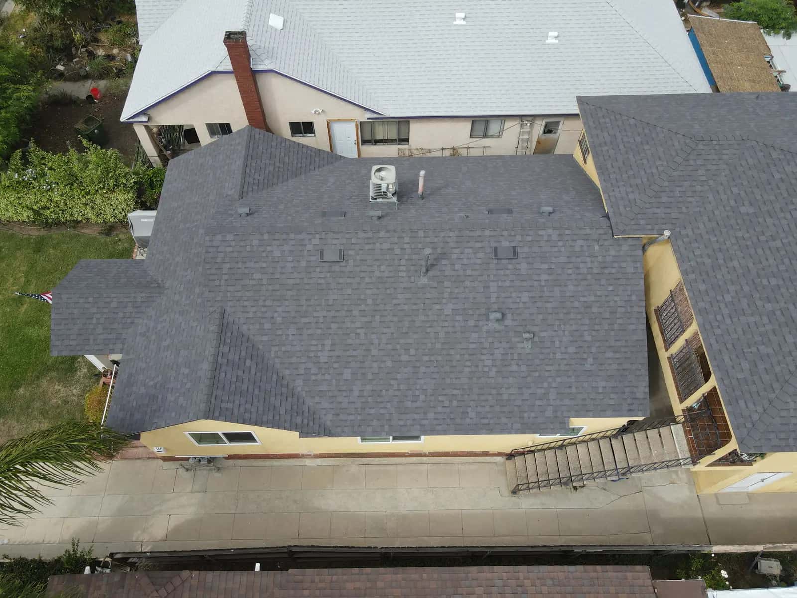 Low aerial view of the new shingle hip roof and exterior stairs along the side of the building
