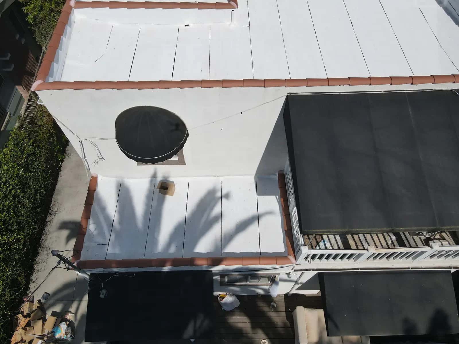 Lower white flat roof section and terracotta-capped parapet above the building’s awnings