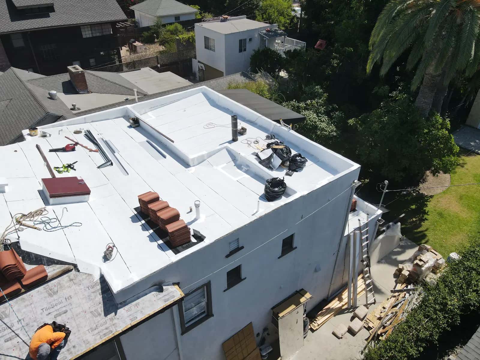 Clay tile and materials staged on the new white flat roof terrace during the work