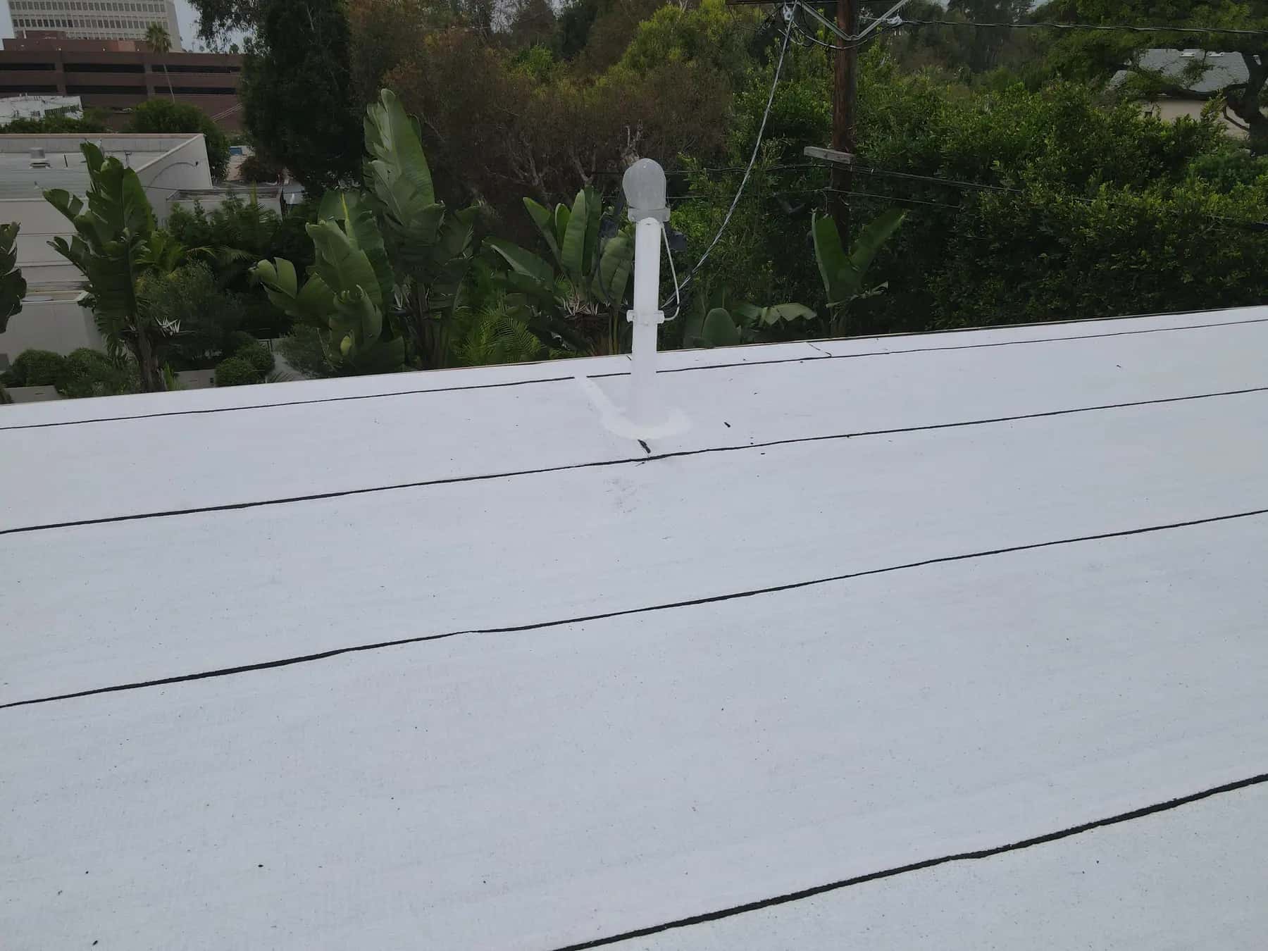 Plumbing vent and its flashing collar on a straight run of the white roof