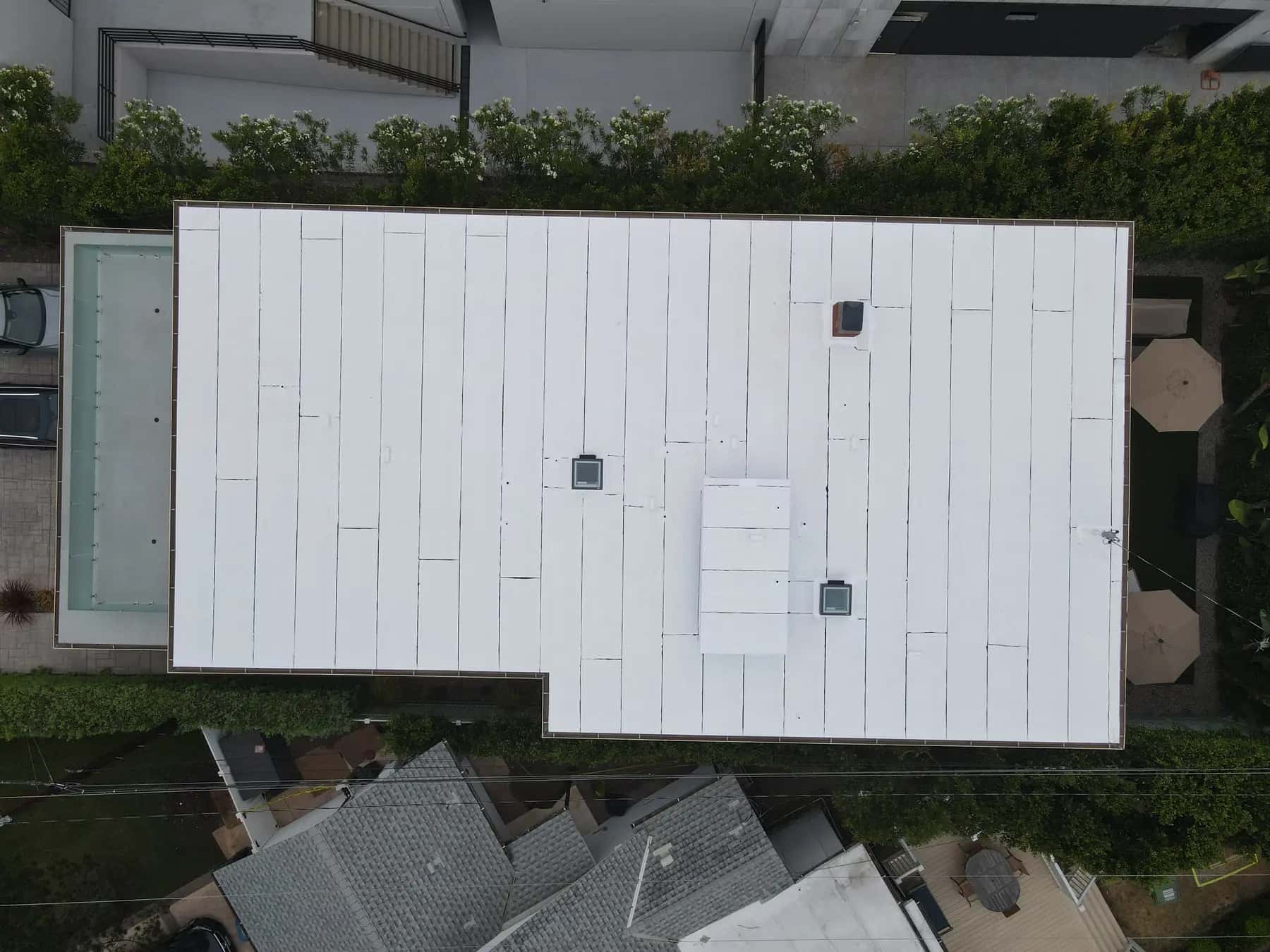 Overhead view of the L-shaped white roof beside the courtyard, with every skylight and the raised window box in place