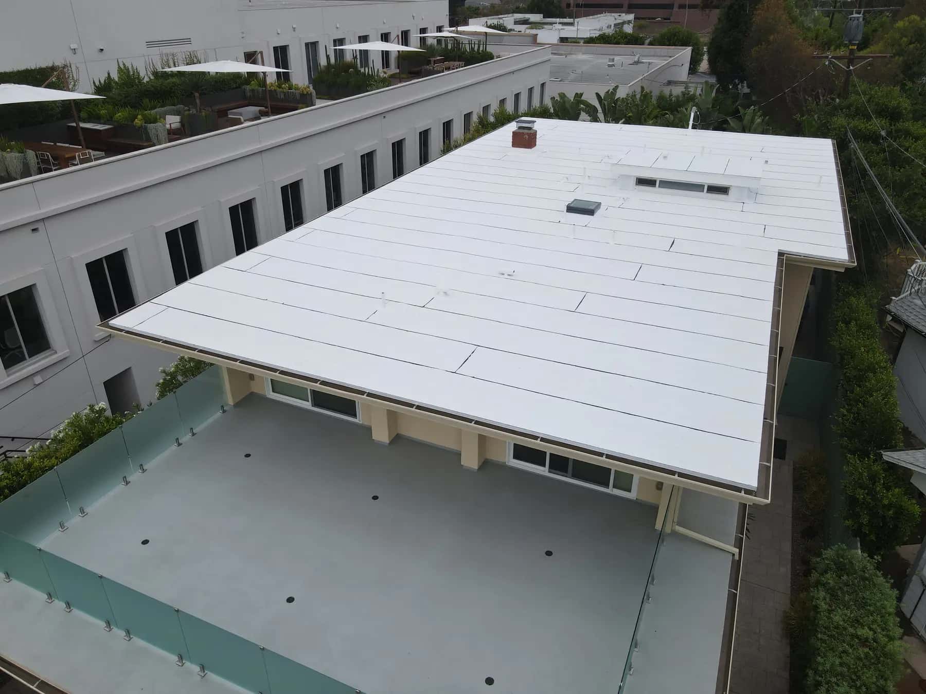 The white flat roof overhanging a lower terrace with a frosted glass railing