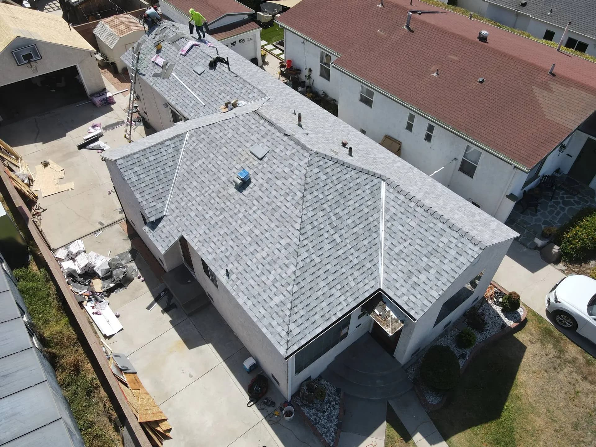 A roofer working near the ridge of a finished shingle roof
