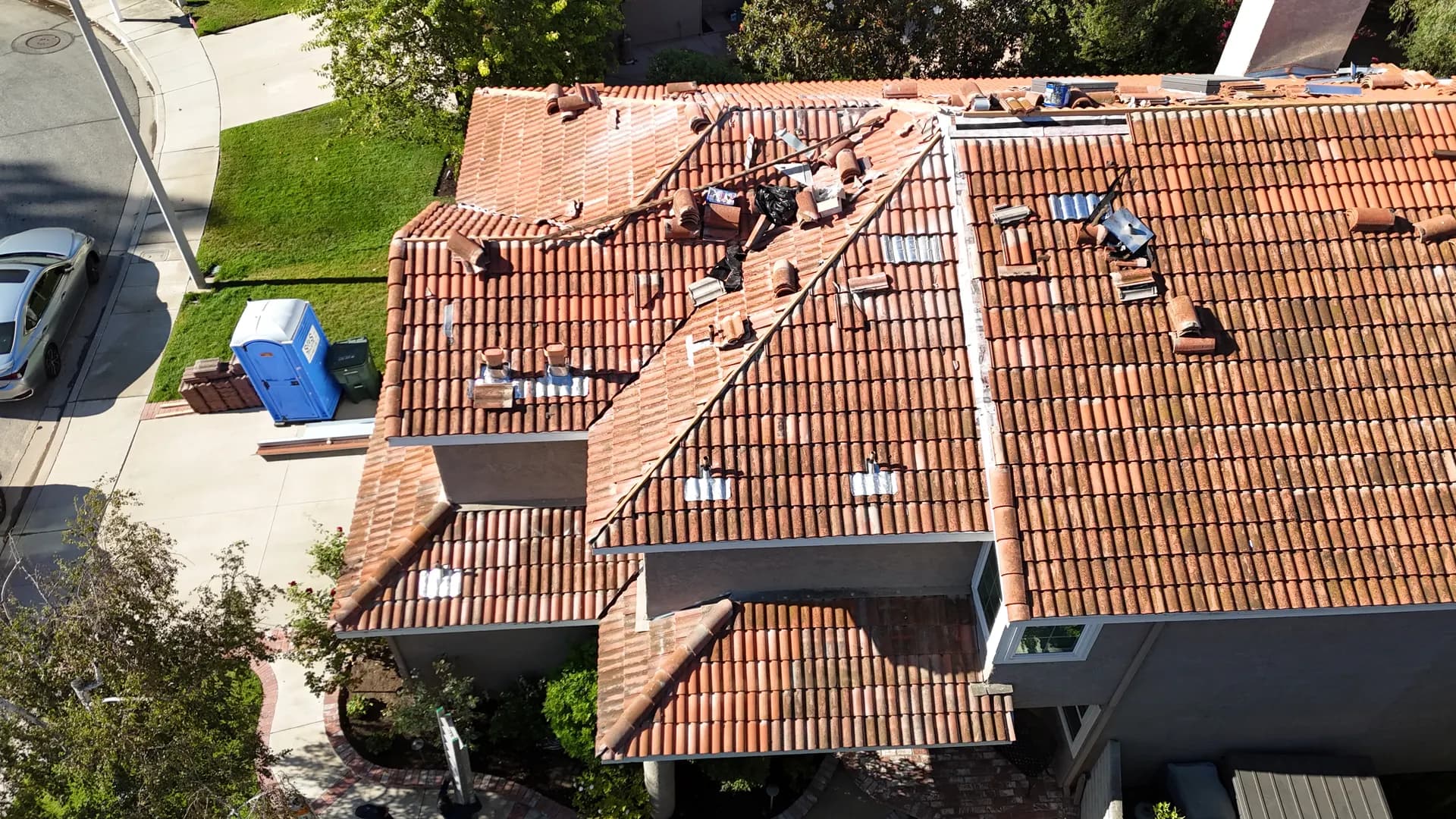 Aerial view of tiles lifted off a roof during a tile lift and relay, exposing the underlayment